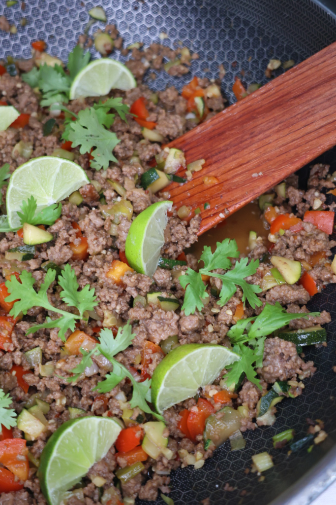 Chili Lime Beef Stir Fry served in a wok with fresh lime wedges and cilantro garnish