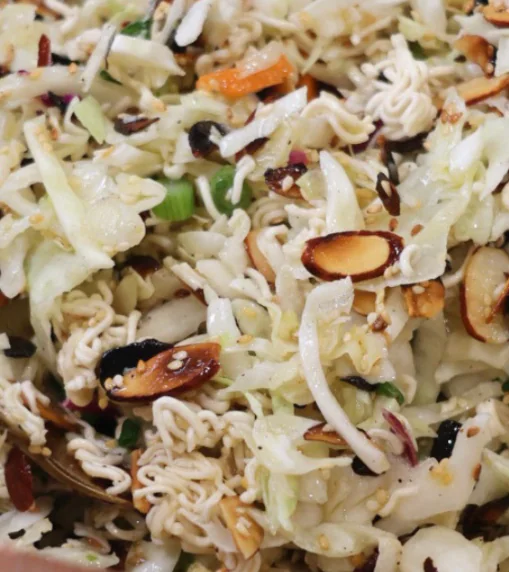 Bowl of Crunchy Ramen Cabbage Salad made with shredded cabbage, green onions, crunchy ramen noodles, toasted almonds, sesame seeds, and a sweet tangy dressing.