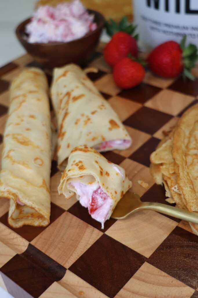 Greek Yogurt Strawberries and Cream Protein Crepes filled with creamy Greek yogurt filling and fresh strawberries on a white plate.