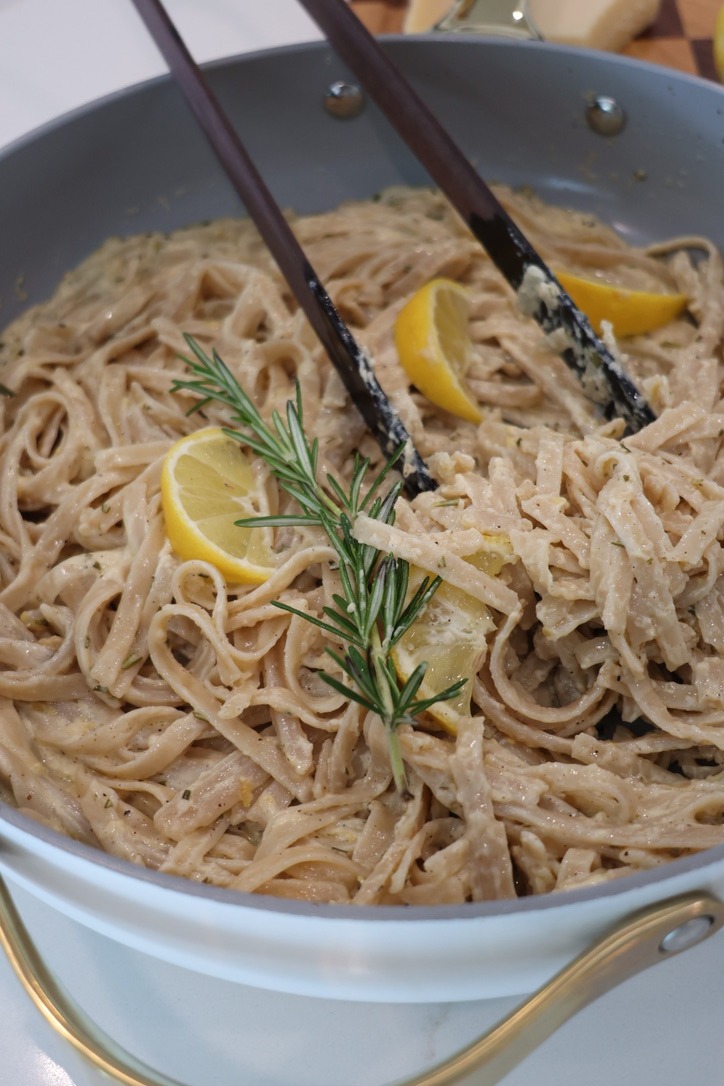 A bowl of creamy lemon fettuccine Alfredo made with gluten-free brown rice fettuccine noodles tossed in a rich sauce of blended cottage cheese, heavy cream, freshly grated Parmesan, garlic, fresh rosemary, lemon juice, and lemon zest. Garnished with extra Parmesan, cracked black pepper, rosemary, and lemon zest for a fresh, high-protein pasta dinner.