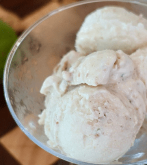 Creamy low-calorie high-protein key lime pie cheesecake ice cream in a Ninja CREAMi pint topped with crunchy cookie pieces and fresh lime zest.