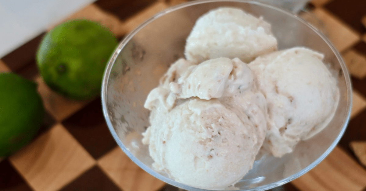 Creamy low-calorie high-protein key lime pie cheesecake ice cream in a Ninja CREAMi pint topped with crunchy cookie pieces and fresh lime zest.