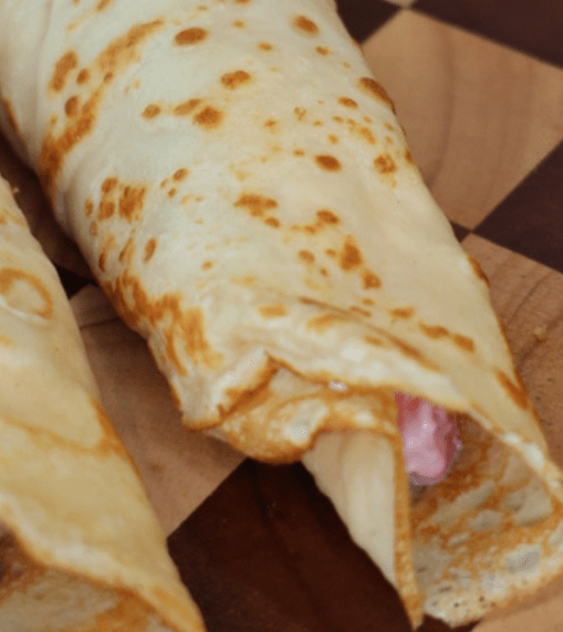 Greek Yogurt Strawberries and Cream Protein Crepes filled with creamy Greek yogurt filling and fresh strawberries on a white plate.