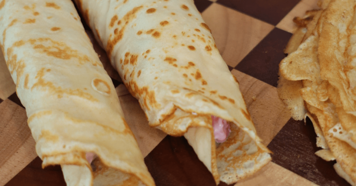 Greek Yogurt Strawberries and Cream Protein Crepes filled with creamy Greek yogurt filling and fresh strawberries on a white plate.